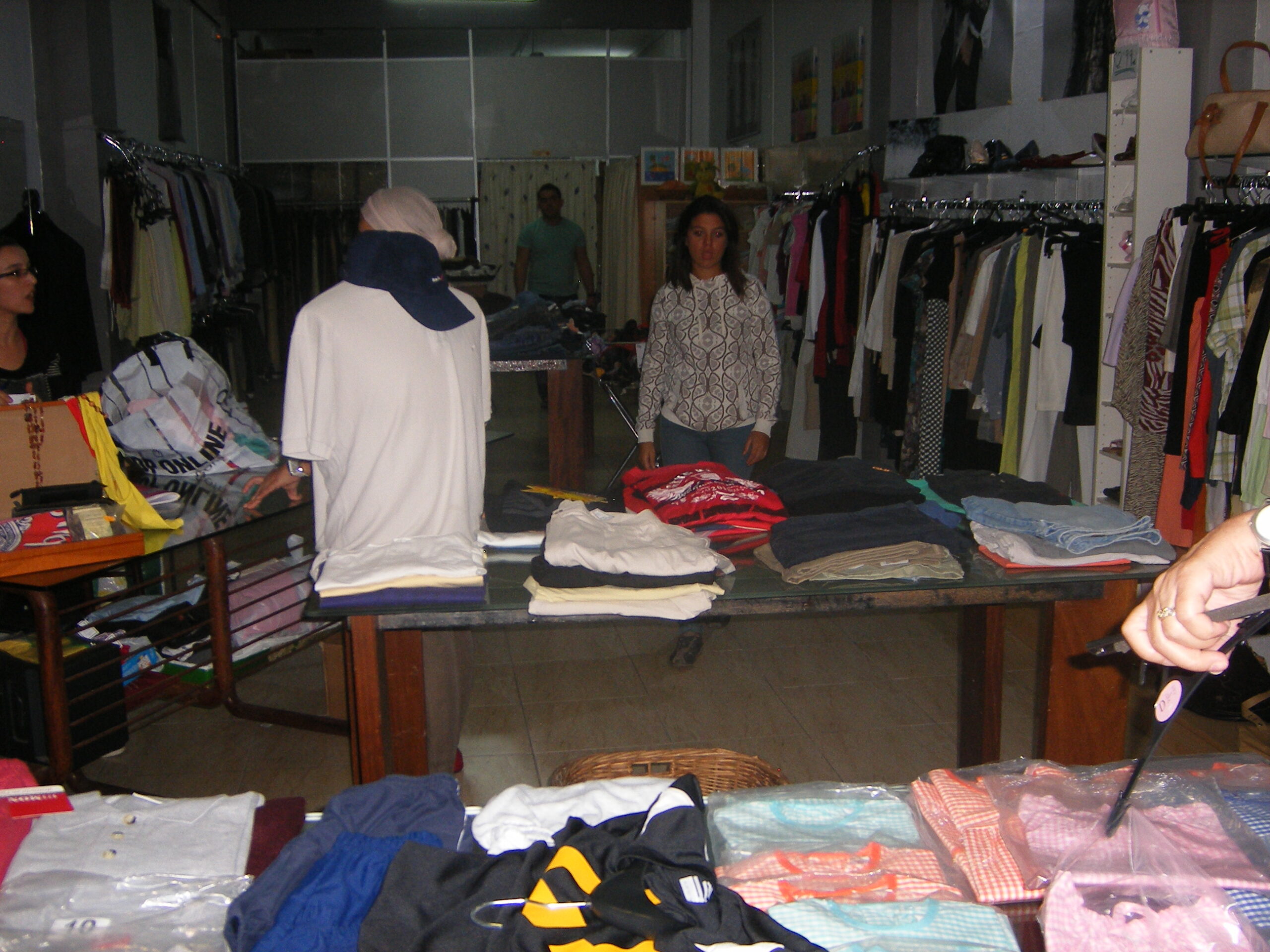 Espacio de distribución de ropa con prendas organizadas en mesas y percheros para personas y familias en situación de vulnerabilidad.