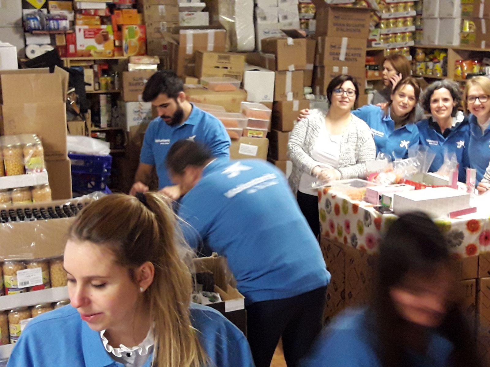 Personas voluntarias organizan y clasifican alimentos en un almacén para su distribución a familias en situación de vulnerabilidad.