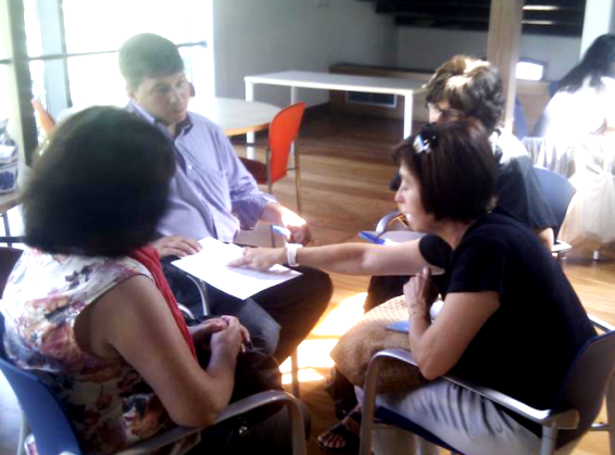 Grupo de mujeres reunidas con un orientador revisando un documento durante una sesión de acompañamiento para la inserción laboral en el sector comercial.