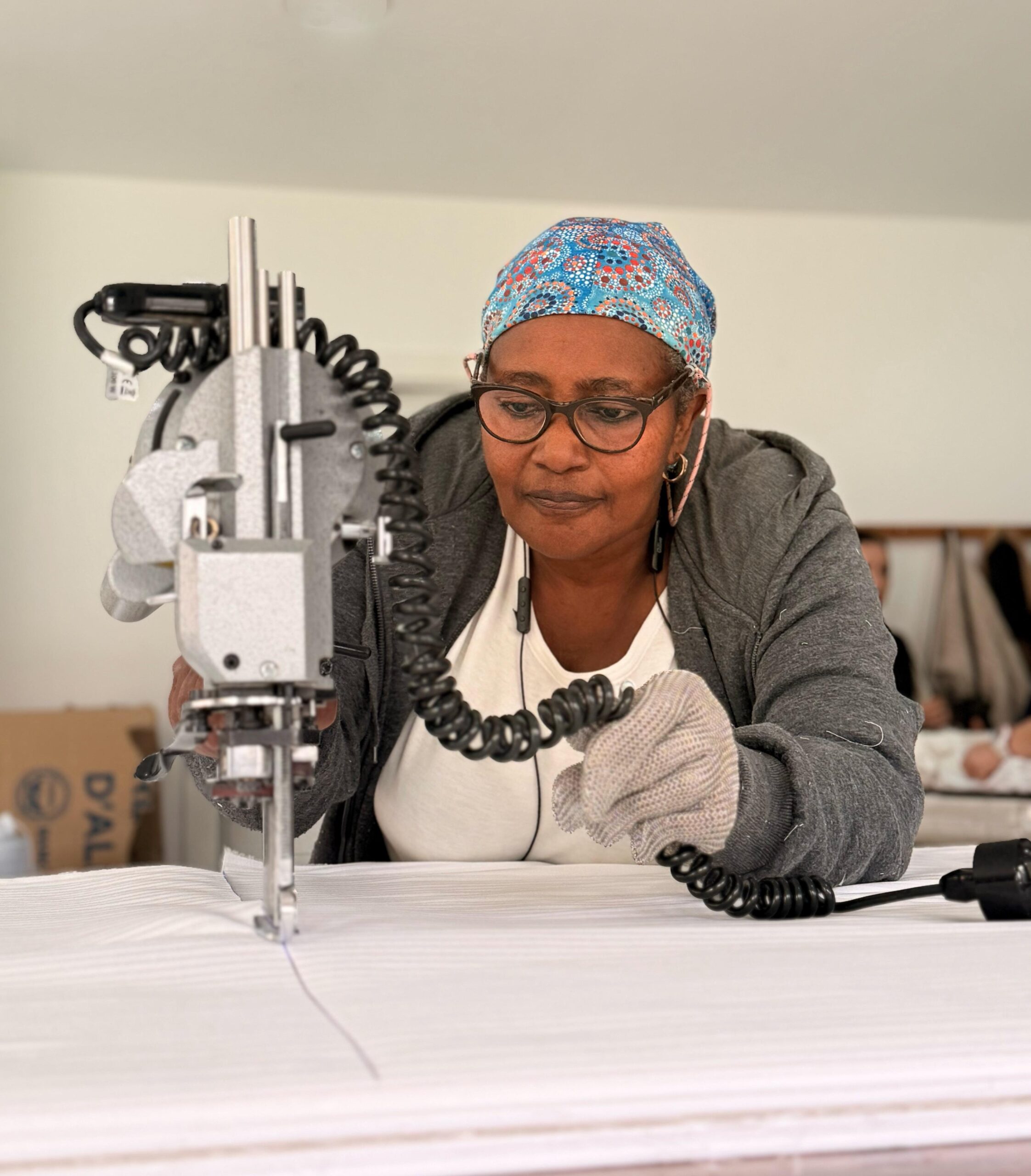 Mujer trabajando con una máquina de coser industrial en el taller textil solidario del Centre Sant Martí.